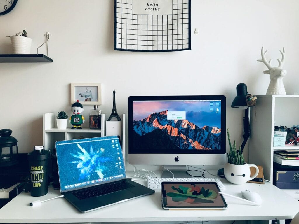 Oportunidades Remotas para CS, DEV e Marketing A stylish home office featuring a laptop, desktop, and artistic decor elements for a productive workspace.