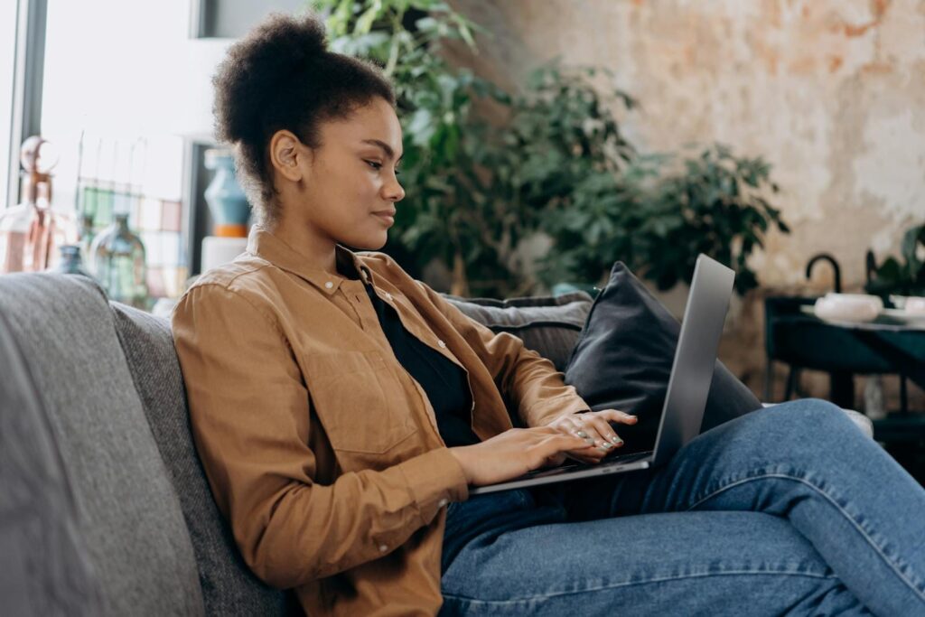 Atendimento ao Cliente Home Office A young woman in casual clothing works on her laptop in a cozy home office setting.