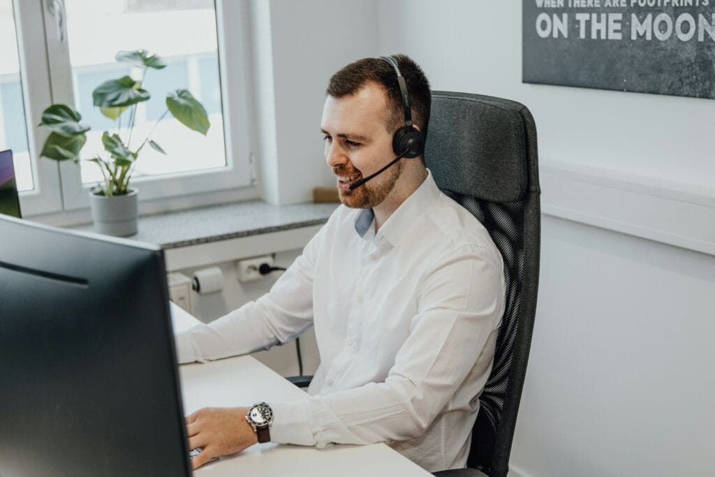 Atendente de Call Center Sem Experiência a man wearing a headset sitting in front of a computer