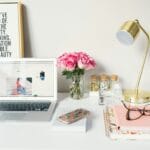 Operador de Call Center Remoto e Designer (Híbrido) MacBook Air beside gold-colored study lamp and spiral books