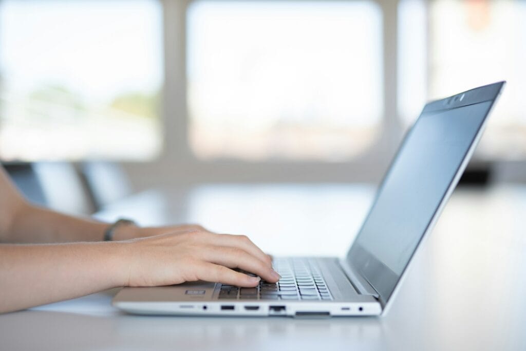 Auxiliar e Assistente Administrativo Remoto a close up of a person typing on a laptop