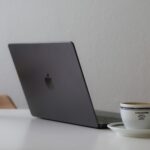 Customer Success Remoto e mais Vagas Home Office Laptop and coffee cup on a white table.