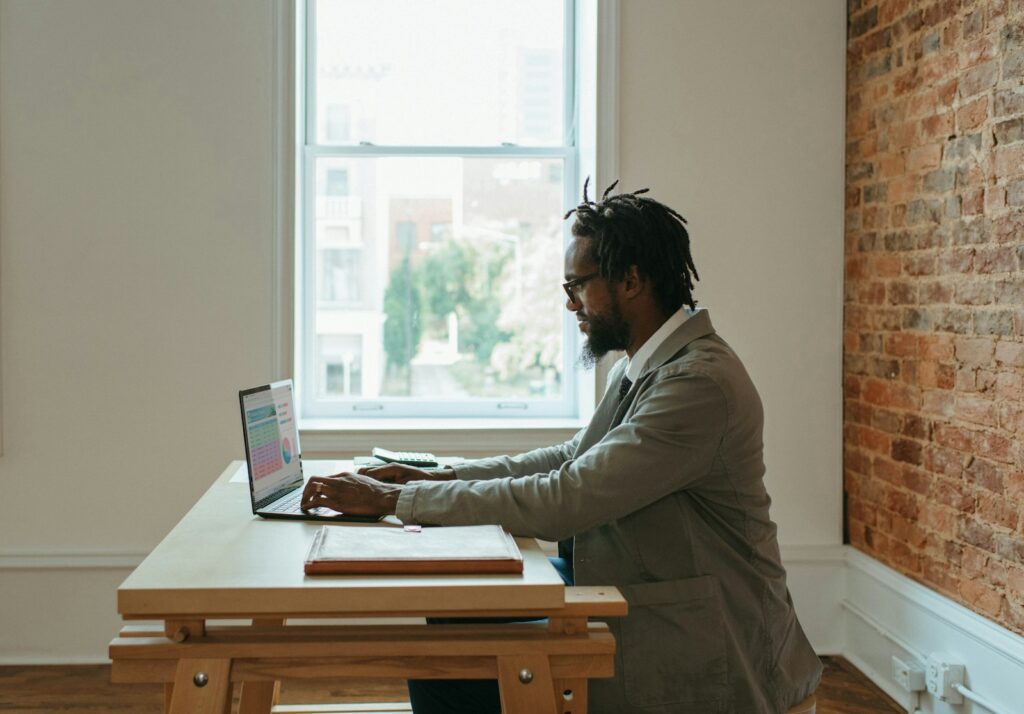 Bold contratando Assistente Administrativo Remoto a person sitting at a desk with a laptop and papers