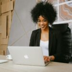 Vagas Remotas na Nasajon Smiling woman working remotely on a laptop in a stylish office setting.