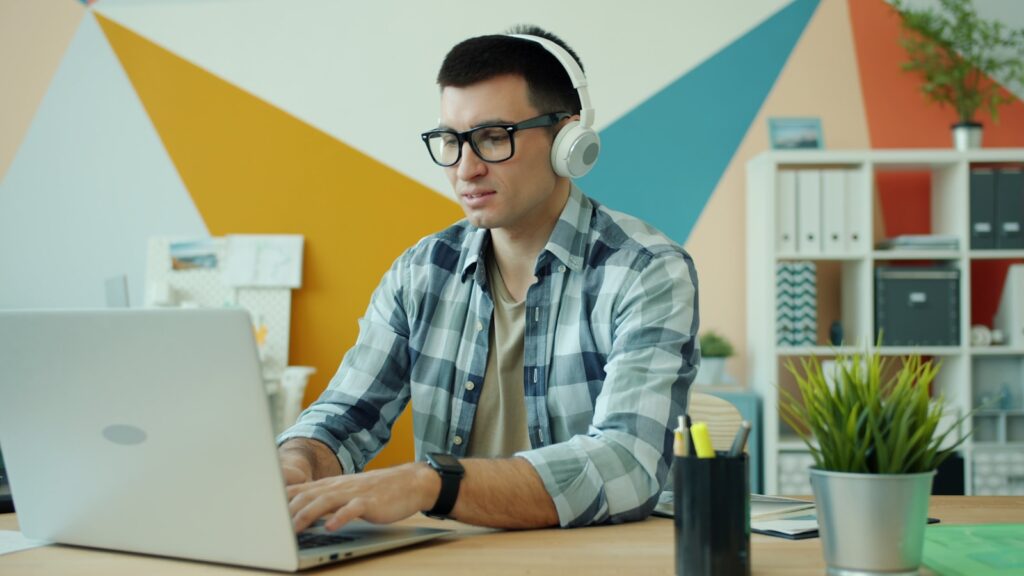 Vagas Remotas na Digital Growth Man wearing headphones works on a laptop.