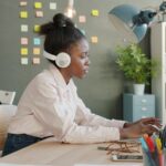 Vagas Home Office na Funcional Health Tech Woman wearing headphones working on laptop at desk.