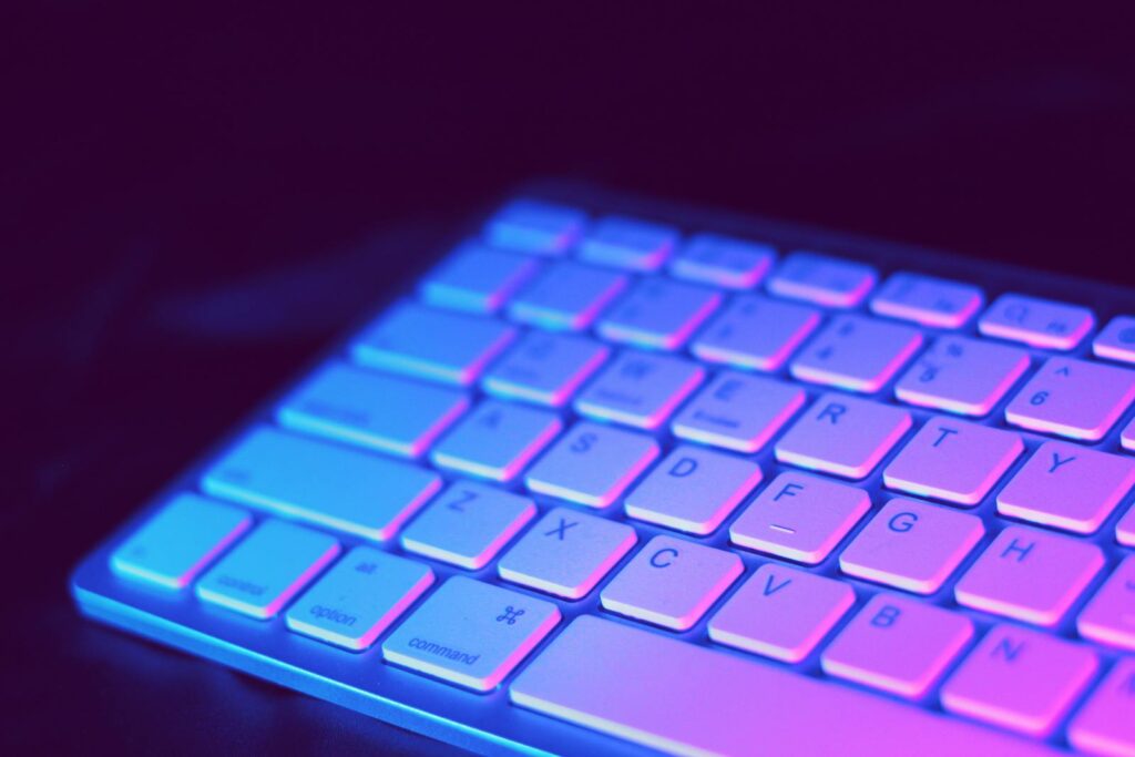 Analista de Customer Success JR Remoto e mais vagas de emprego! Close-up of a modern keyboard illuminated with vibrant purple and blue neon lighting.