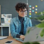 14 Vagas Remotas na SoftDesign Young woman working on a laptop in an office.