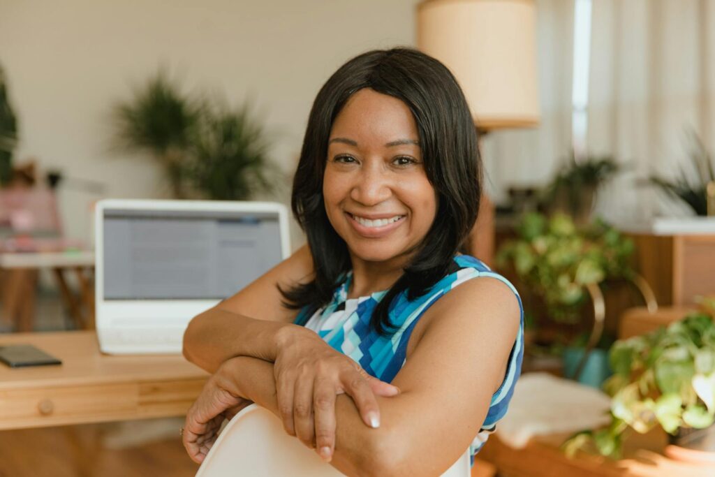 Vagas Remotas na ZG Soluções A smiling businesswoman sits confidently at her desk in a modern office setting.