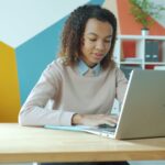 Jovem Aprendiz e + Vagas Remotas com VA/VR de R$ 1.000,00 Woman typing on a laptop at a desk.