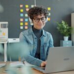 72 Vagas Remotas na Stefanini, com VR/VA de R$ 700,00 Young woman with headphones working on laptop in office