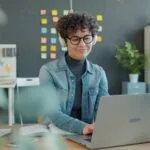 72 Vagas Remotas na Stefanini, com VR/VA de R$ 700,00 Young woman with headphones working on laptop in office