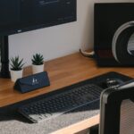 Analista de CS e +Vagas Remotas com VR de R$ 900,00 a desk with a computer monitor, keyboard, mouse and a plant