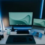 Vagas Remotas na Yampi com R$ 1047 de VR A sleek and modern desk setup featuring a monitor, laptop, and ambient lighting, perfect for productivity.