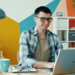 Vagas 100% Remotas na Avenue Man working on a laptop in a colorful office.