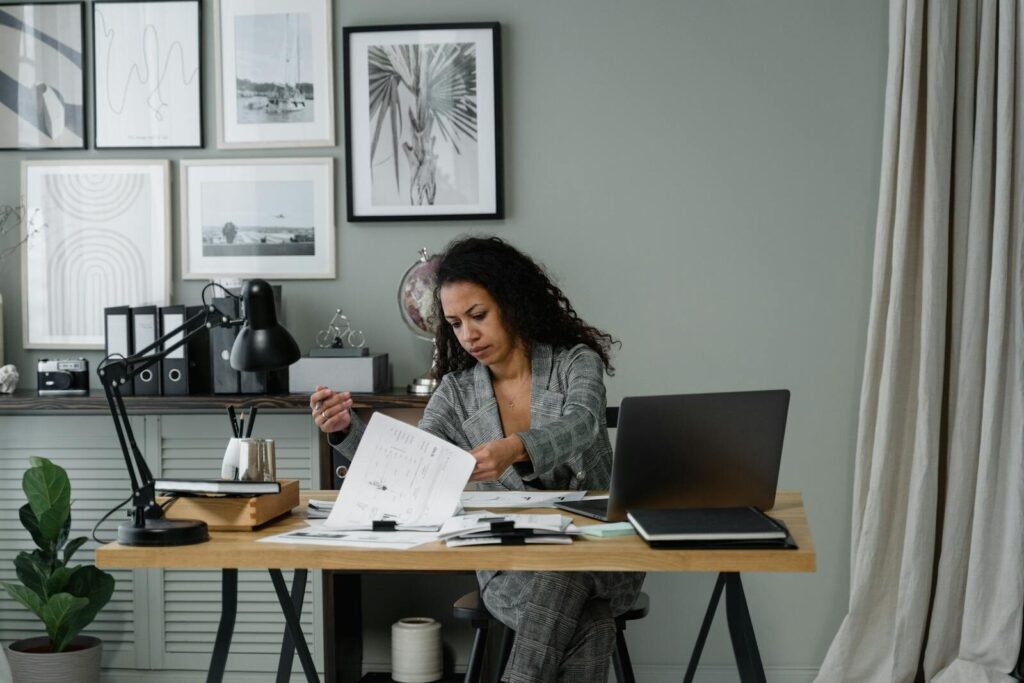Mercafacil contrata para Home Office, VA/VR de R$ 900,00 Professional woman working at a desk in a stylish home office setting with decor and gadgets.
