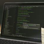 Vagas Remotas na FourHands, com salário até R$ 13.500 Laptop screen displaying lines of code with a coffee mug.