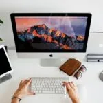 Emprego Remoto na TOTVS, VA/VR de R$ 950 person using silver imac and apple magic keyboard