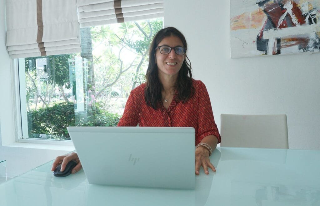 Vagas Remotas na Minsait Woman works on laptop at a bright, modern table.