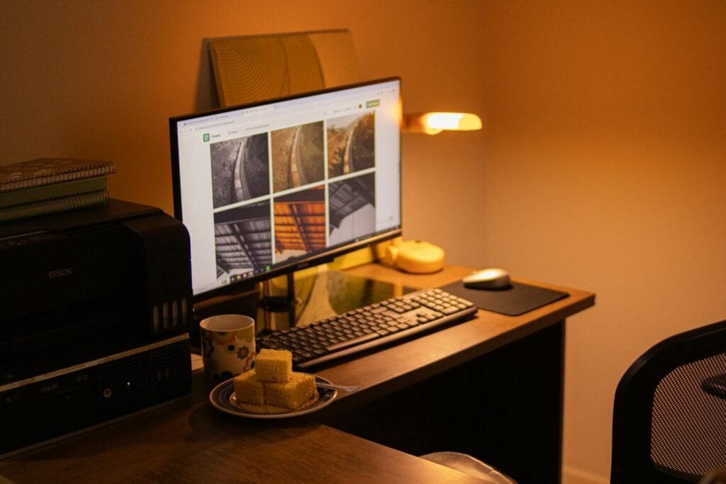 Remotas na Vivo Digital, com VA/VR de R$ 1.400 Warm-toned home office with computer setup, snacks, and ambient lighting.