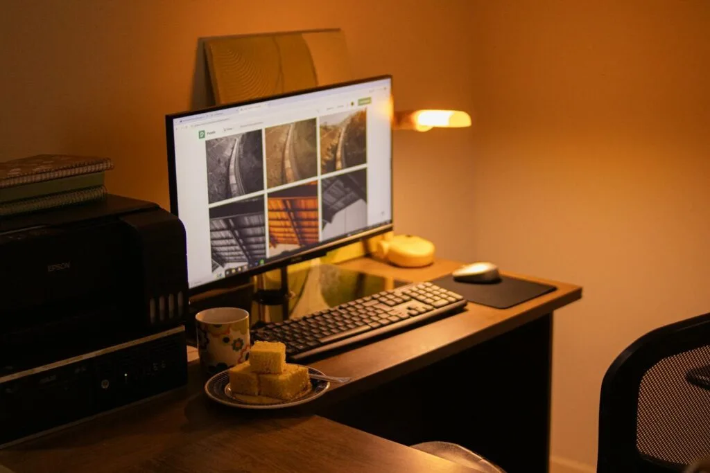 Remotas na Vivo Digital, com VA/VR de R$ 1.400 Warm-toned home office with computer setup, snacks, and ambient lighting.