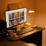 Remotas na Vivo Digital, com VA/VR de R$ 1.400 Warm-toned home office with computer setup, snacks, and ambient lighting.