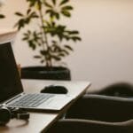 Vagas Remotas na Verity, com VA/VR de R$ 930,00 A cozy home office workspace with a laptop, headphones, and a plant. Ideal for remote work.