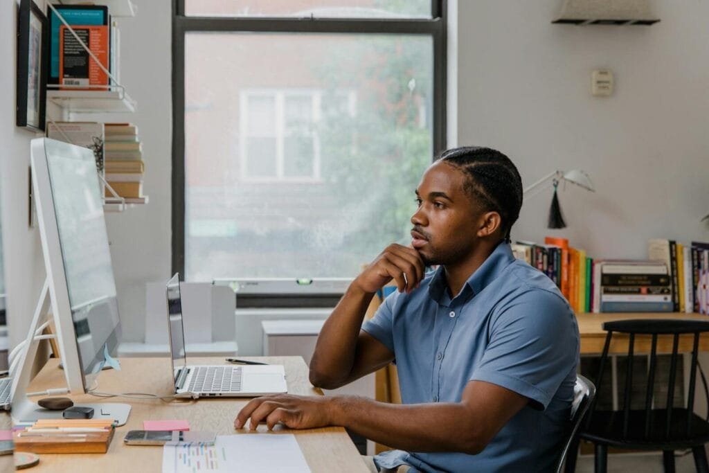 Remotas na ED, com VA/VR de R$ 700,00 Adult man concentrating at his home office desk with computer, books, and natural light.