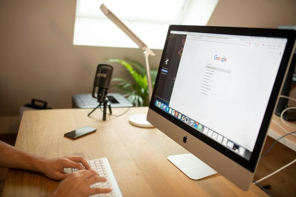 Vagas Remotas na LWSA, com VA/VR de R$ 800,00 A modern workspace with an iMac displaying Google search, perfect for remote work setups.