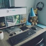 Teletrabalho com VR/VA até R$ 1.500! A tidy home office desk setup with a computer, keyboard, and personal items, creating a cozy work atmosphere.