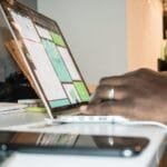 Ativa GR contratando para Home Office Focused setup of person working on a laptop in a home office environment with technology and documents.