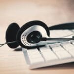 Analista de Sucesso do Cliente Remoto com R$ 1.012,50 de VA/VR a pair of headphones sitting on top of a keyboard