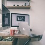 Vagas 100% remotas para Auxiliares Administrativos Sleek home office setup with dual monitors, a laptop, and minimalist decor.