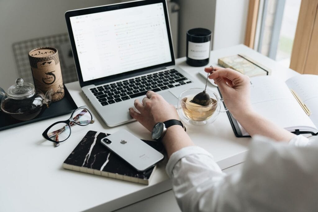 Home Office com VA/VR de R$ 1.200,00 A cozy home office scene with a laptop, tea, and workspace essentials.