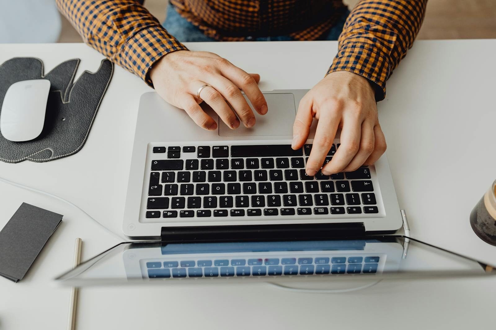 Vagas Remotas com R$ 932 de VR/VA Hands typing on a laptop keyboard in a modern home office environment.