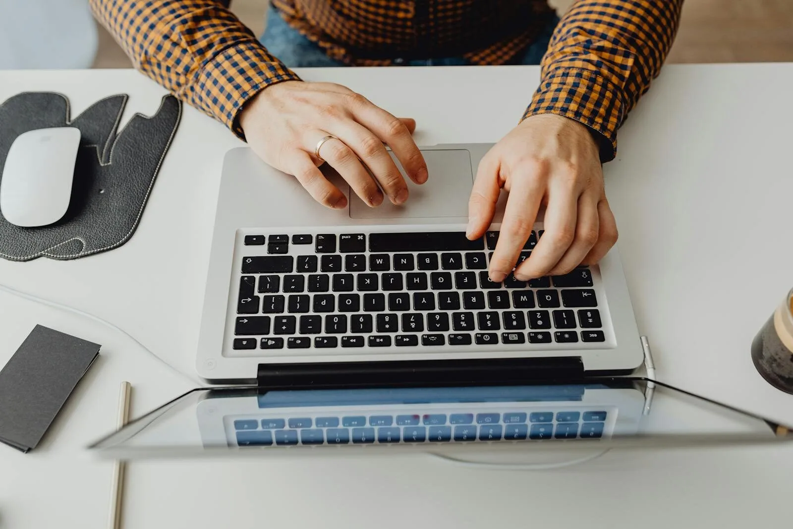 Vagas Remotas com R$ 932 de VR/VA Hands typing on a laptop keyboard in a modern home office environment.