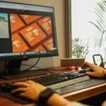 Atendimento Júnior e +Vagas Remotas com R$ 1.700 de VR/VA Hands working on a computer in a modern office setting, showcasing a focused and productive environment.