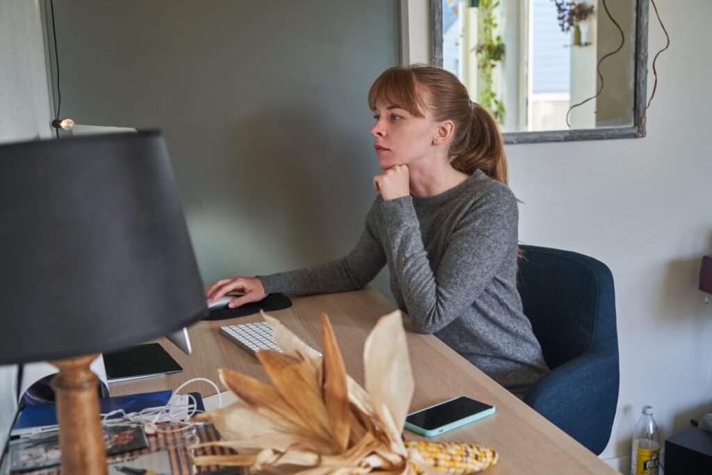 Analista de TI e mais Remotas com VA/VR de R$ 700,00 Caucasian woman intently working on a computer at her home office, emphasizing focus and productivity.