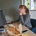 Analista de TI e mais Remotas com VA/VR de R$ 700,00 Caucasian woman intently working on a computer at her home office, emphasizing focus and productivity.