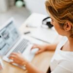 Vox Tecnologia: Remotas com VA/VR de R$ 800,00 A woman focused on her laptop in a modern home office setting, showcasing productivity.