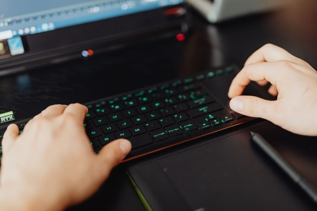 Remotas na Cadastra, com VR de R$ 700,00 Closeup of hands typing on an RGB keyboard in a modern office setting.