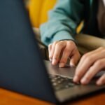 Customer Success Remoto e + vagas com VA/VR de R$ 950 Crop unrecognizable distance employee surfing internet on netbook while working on project at desk in room
