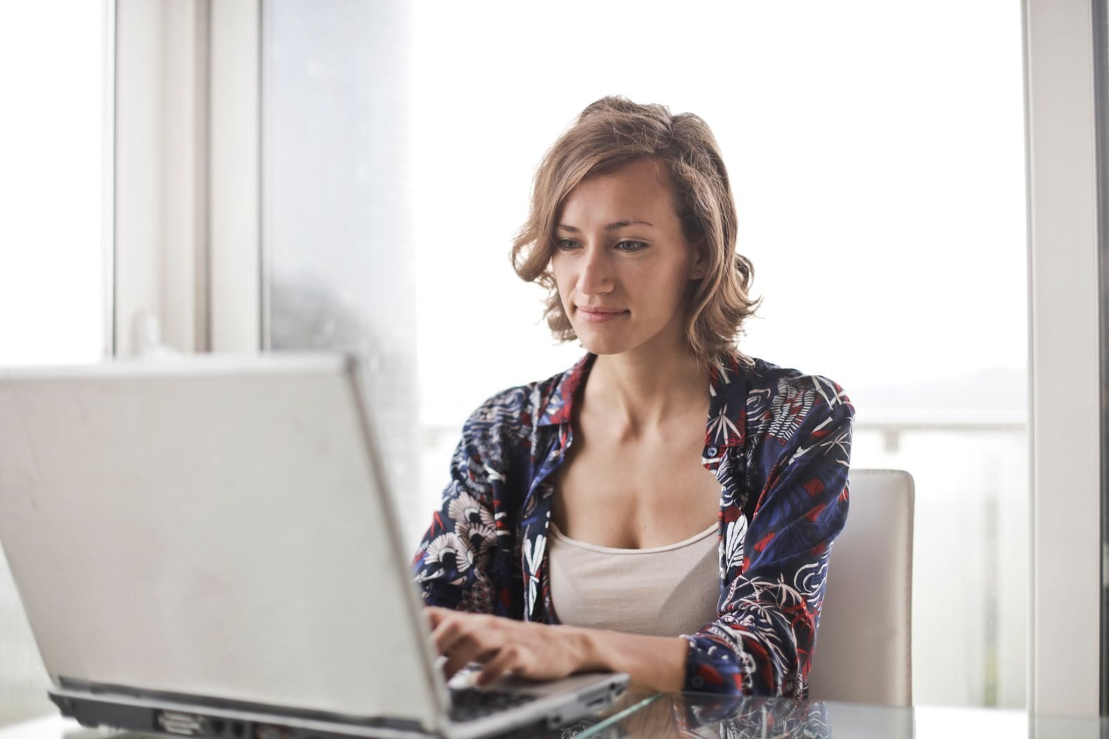 Trabalho Remoto na Spread, VA/VR de R$ 800,00 A woman typing on a laptop in a bright, modern home office setting.