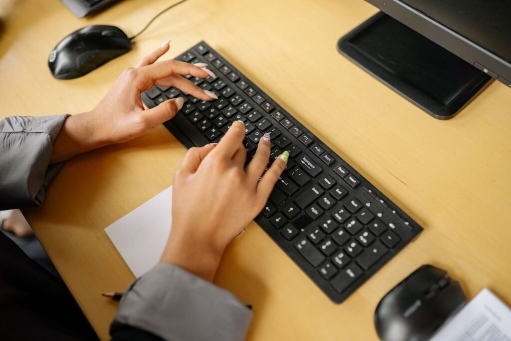 Customer Success com VA/VR de R$ 1.000 Hands typing on a keyboard in an office environment, viewed from above.