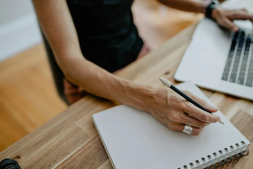 Teletrabalho com VA/VR de R$ 700,00 a person writing on a piece of paper
