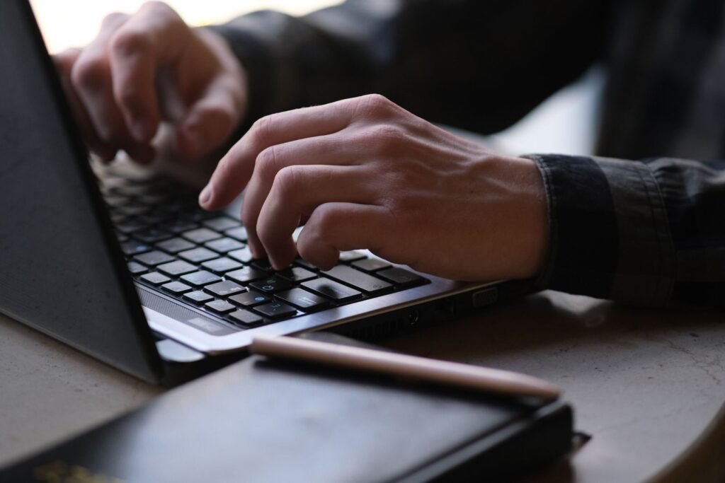Remotas na Ícaro Tech com R$ 1.000 de VA/VR Close-up photo of hands typing on a laptop, perfect for remote work or digital nomad themes.