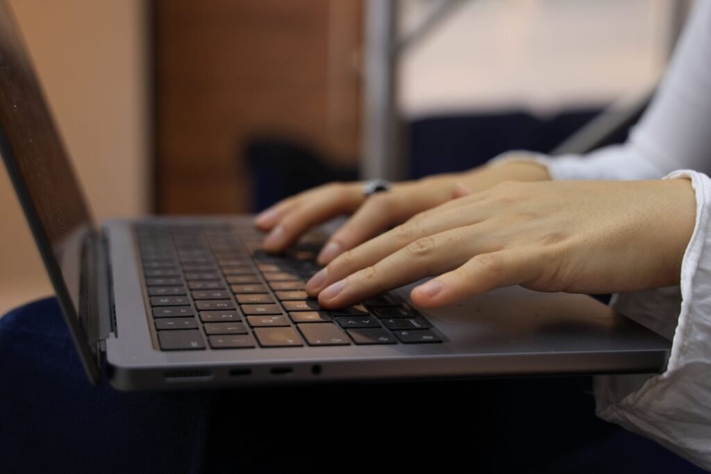 Remotas na ContaJá, R$700,00 de VA/VR e + Hands typing on a laptop keyboard in an indoor setting. Perfect for business and technology themes.
