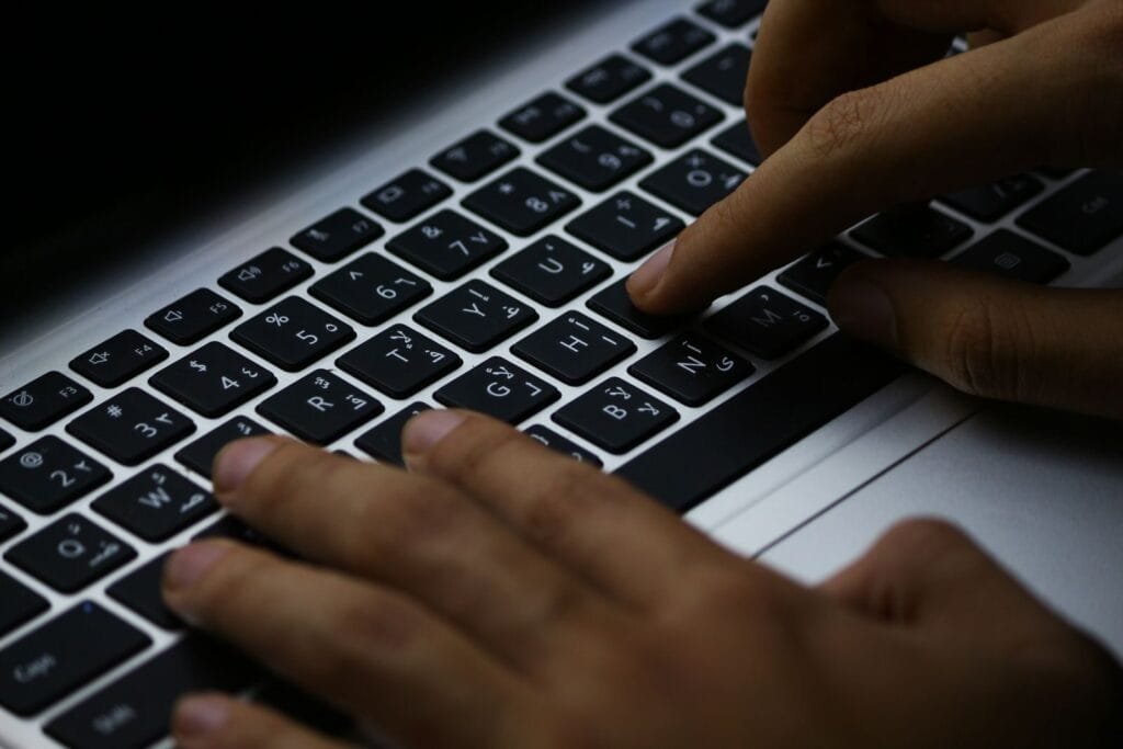 Remotas com R$ 1.000 de VA/VR na Afinz Focused typing on a laptop's illuminated keyboard, enhancing productivity in a digital workspace.