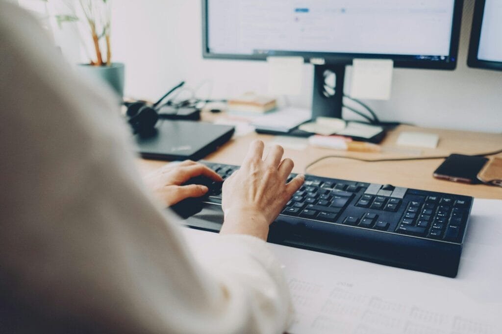Vagas Remotas na com VA/VR de R$ 1.000 a person is typing on a computer keyboard