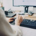 Vagas Remotas na com VA/VR de R$ 1.000 a person is typing on a computer keyboard